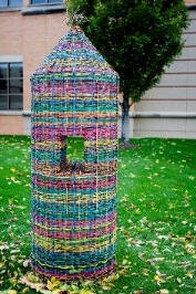 Colorful sculpture in the shape of a pencil with a hole in through middle.
